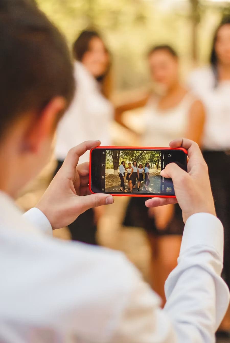 Junge fotografiert mit dem Handy eine Gruppe